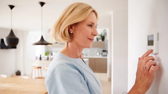 Kvinna reglerar temperaturen i hemmet.