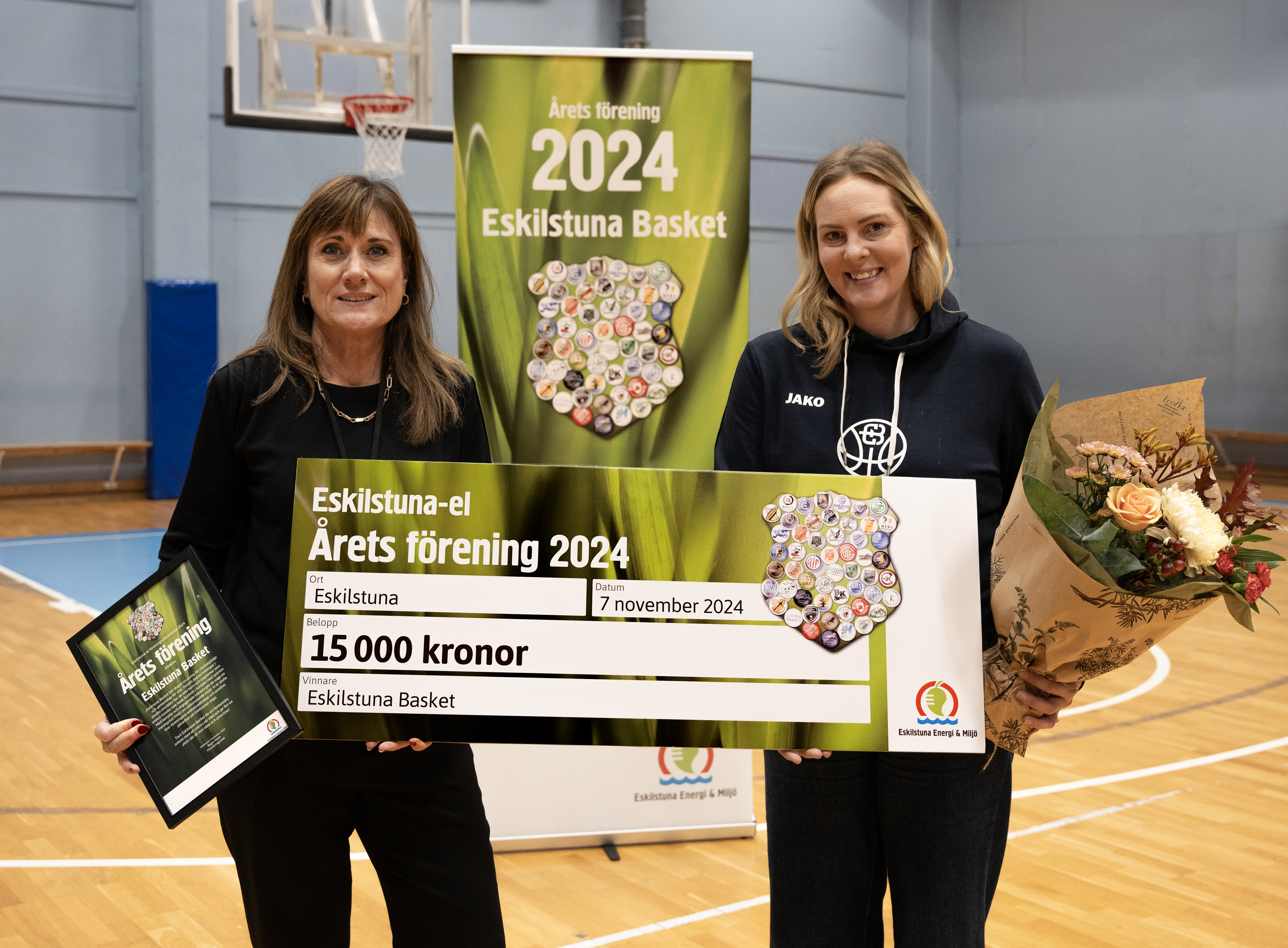 Kimona Hogestadh, ordförande i Eskilstuna Basket, tar emot vinnarchecken från Ulrika Thorén på Eskilstuna Energi och Miljö.